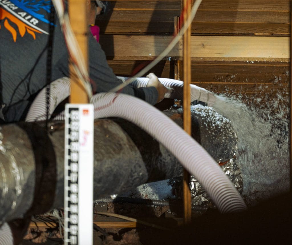 Beluga Air technician installing blow in insulation in a customer attic